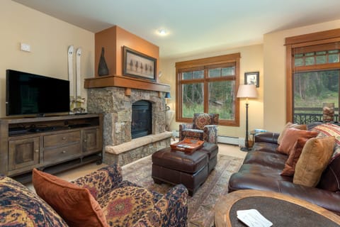 Sink into plush leather sofas by your crackling stone fireplace while forest views frame your cozy mountain retreat.