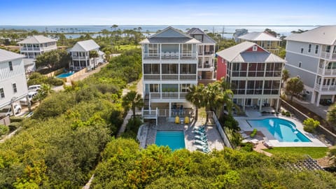 Aerial view of this coastal property and its surrounding beachside neighborhood, showcasing the multiple private pools and easy access to the waterfront area.