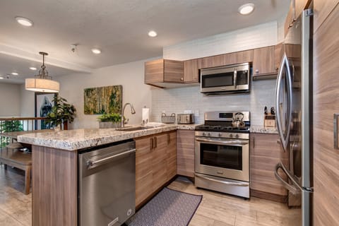 New kitchen with custom cabinets, stainless appliances, 6-burner gas stove, granite counters, and 3 bar seats