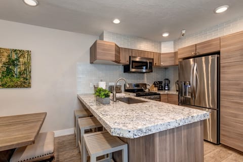 New kitchen with custom cabinets, stainless appliances, 6-burner gas stove, granite counters, and 3 bar seats