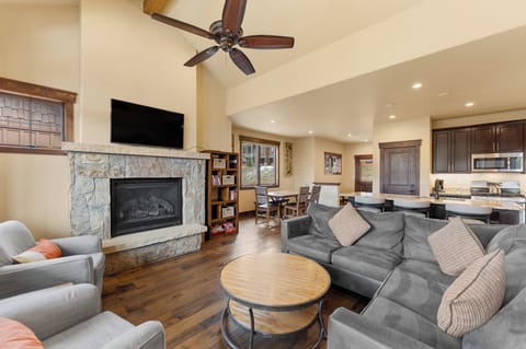 Relax in your spacious living room with stone fireplace, plush seating, and warm wood accents creating the perfect mountain retreat ambiance.