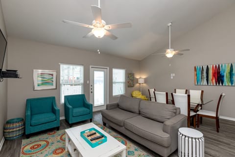 Relax in your bright, modern living space with cozy seating, ceiling fans, and colorful artwork that creates a welcoming home-away-from-home atmosphere.