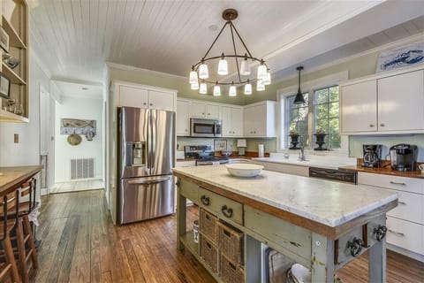 Main level kitchen - This roomy main-floor kitchen mixes old-Tybee charm with today’s comforts. The marble center island and eye-catching lighting steal the show.