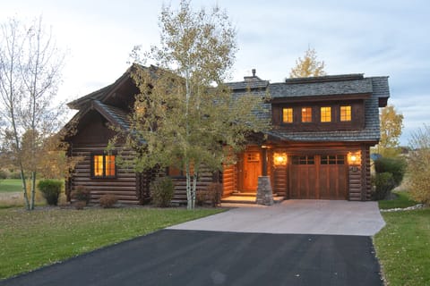 Step into your own rustic mountain retreat! This charming log home glows warmly at dusk, surrounded by peaceful autumn trees and manicured lawns that invite evening strolls.
