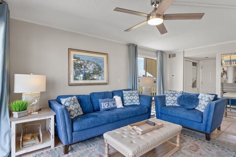 Relax in this bright coastal living space featuring comfortable seating, stylish beach-inspired décor, and easy access to the private patio overlooking the golf course. A perfect spot to unwind after a day in the sun.