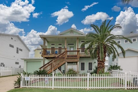 Front exterior — Starkey Properties sign, wood staircase, white picket fence, and palm tree