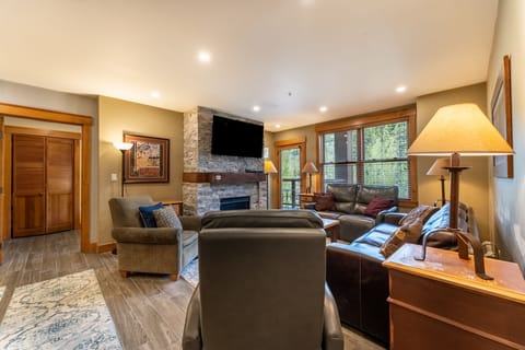 Sink into plush leather seating by your stone fireplace, where mountain views and warm lighting create your perfect evening retreat.