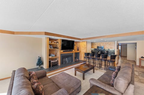 Relax in your spacious living area featuring plush sectional seating, cozy fireplace, and open kitchen with breakfast bar for memorable gatherings.