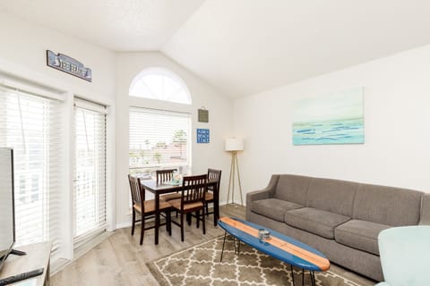 Unwind in your coastal-themed living space with comfy seating, beach-inspired decor, and abundant natural light streaming through shuttered windows.