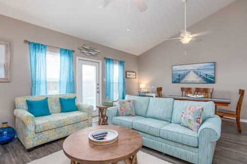 Relax in your coastal-themed living space with soft blue sofas, nautical artwork, and tropical touches creating a peaceful beach house atmosphere.
