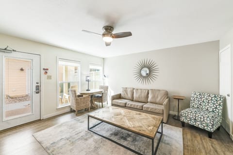 Step into your bright, airy living room where modern style meets comfort. Natural light fills the space, highlighting the sunburst mirror and inviting seating arrangements. Glass doors open to your private outdoor retreat.