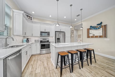 Your coastal-chic kitchen gleams with quartz counters and stainless steel appliances—perfect for morning mimosas or a fresh seafood feast.