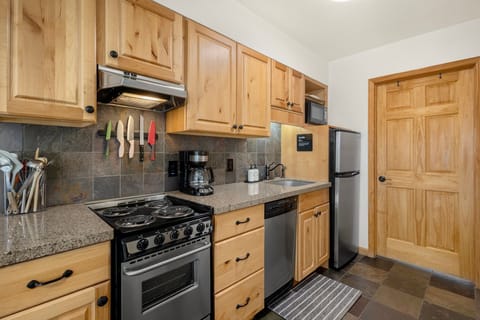 A compact kitchen fully equipped with everything you need—including a full fridge, oven, range, microwave, and dishwasher—for easy meal prep.