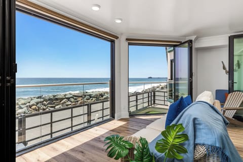 Perfect Place to Lay Back and Watch as the Sun Sets space, where floor-to-ceiling windows frame endless blue waters and golden sand.