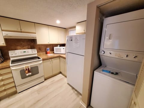 Compact, fully-equipped kitchen with adjacent in-unit laundry facilities.