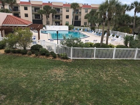 Inviting shared pool area with loungers and a grassy foreground.