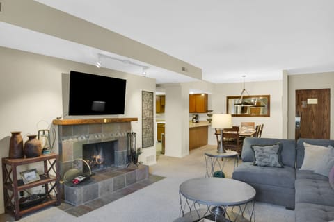 Park Station 122's living room has grey furniture and a gas burning fireplace with flat screen TV mounted above it.