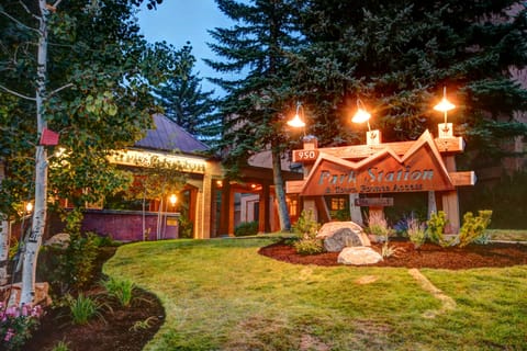 Park Station Condomium sign with lights above it, and evergreen trees and a grassy lawn surround it.