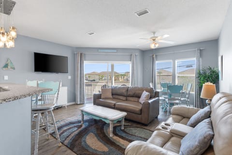Relax in your spacious living area with plush seating, modern TV, and bright windows overlooking the peaceful neighborhood.