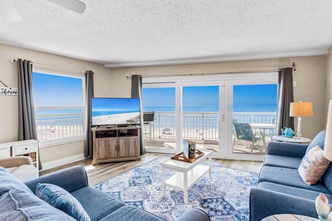 Sink into plush blue sofas while endless ocean views fill your floor-to-ceiling windows, creating your perfect beachfront retreat.