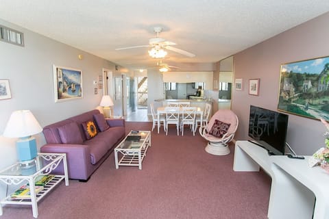 - Spacious living area with plush sofa, accent chairs, and tropical decor touches
- Large windows and balcony access create a bright, airy atmosphere
- Perfect spot to unwind after the beach with movies or family games