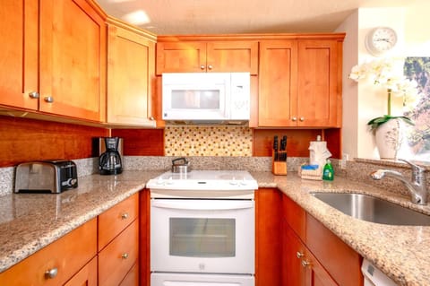 Cook with ease in this sunlit kitchen with granite countertops, full appliances, and tropical-inspired accents