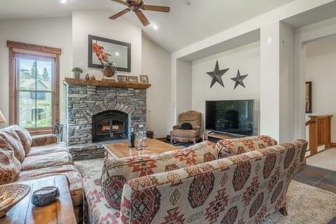 Sink into plush sofas by the stone fireplace and gather around your entertainment center in this inviting living room, where high ceilings and warm wood accents create the perfect mountain retreat for your group.