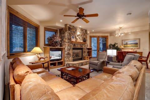 Sink into plush leather seating by your stone fireplace, where warm lighting and mountain views create the perfect evening retreat.