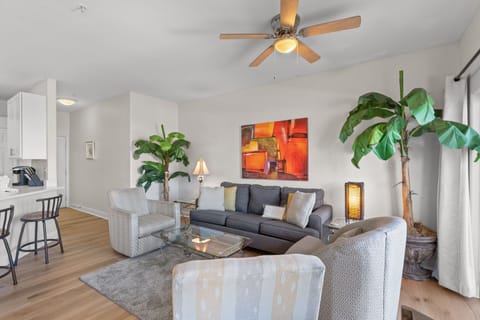 Relax in your stylish living room with comfortable seating, tropical plants, and modern artwork creating a warm, inviting atmosphere for your stay.