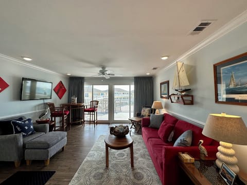 Relax in your spacious nautical-themed living room with comfortable seating, flat-screen TV, and sliding doors to your private balcony.