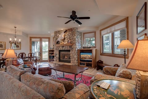 Unwind in this cozy living room where rustic stone fireplace warmth meets comfortable seating for perfect mountain evenings together.