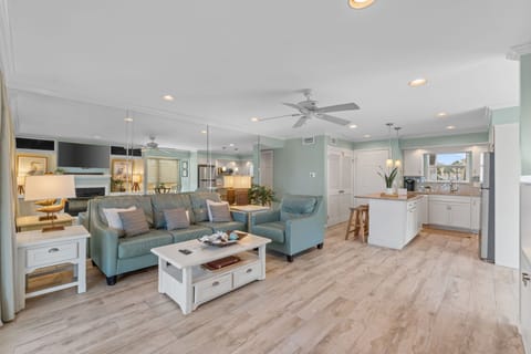Relax in your spacious open-concept living area where coastal blue furnishings and warm wood floors create the perfect beach retreat atmosphere.