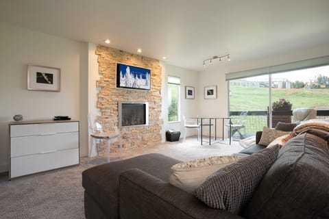Unwind in your cozy living space featuring a stone fireplace, comfortable sectional, and bright windows overlooking peaceful greens.