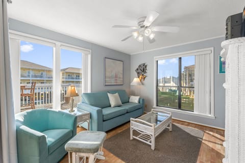 Settle into your coastal-inspired living space, where soft teal furnishings, gleaming hardwood floors, and ocean-themed accents create a soothing retreat after your beach adventures.