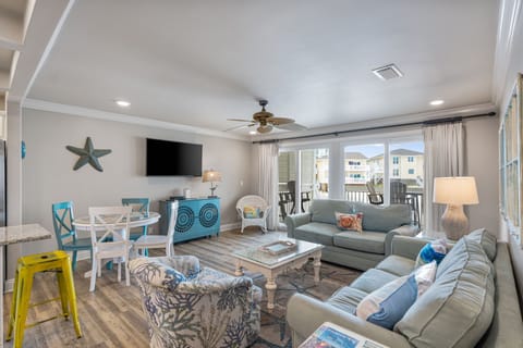Step into your bright, beachy living room where coastal charm meets comfort—plush seating, charming accents, and a balcony invite you to unwind in style.