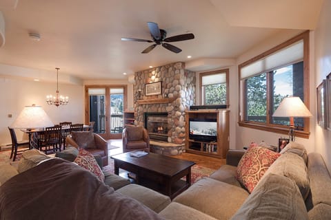 Sink into plush sofas by your stone fireplace, where mountain views through picture windows create the perfect backdrop for cozy evenings together.