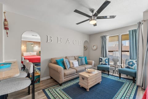 Relax in this bright coastal living room with comfy seating, beach-themed decor, and your own private balcony access for morning coffee.