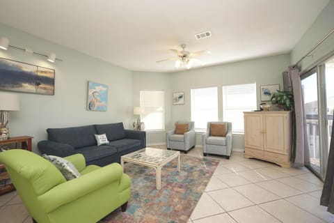 Unwind in your bright, coastal-themed living room featuring comfortable seating and peaceful ocean artwork that creates the perfect vacation atmosphere.
