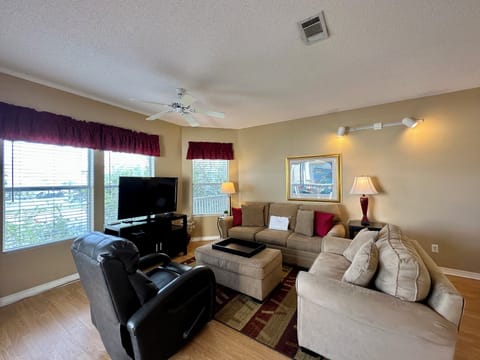 Unwind in your spacious living room with plush sectional seating, flat-screen TV, and warm natural light streaming through large windows.