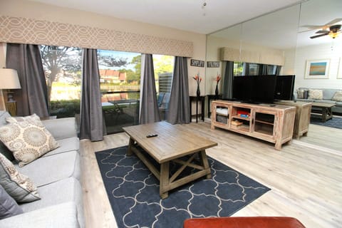 Spacious living room with large windows that let in natural light and flat screen TV