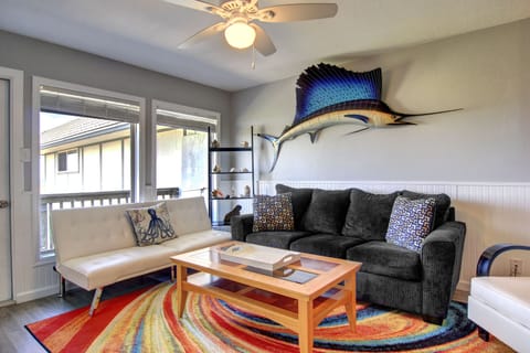 Unwind in your colorful coastal living room with comfy seating, vibrant artwork, and a peaceful neighborhood view from your windows.