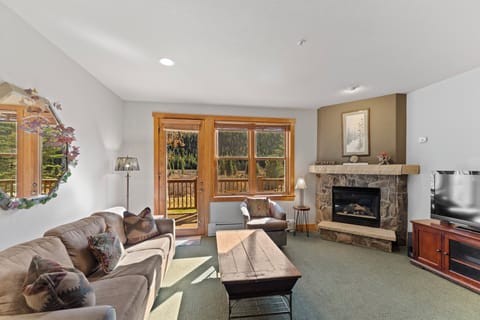 Cozy up in your mountain retreat with a crackling fireplace, plush seating, and stunning forest views through expansive windows.