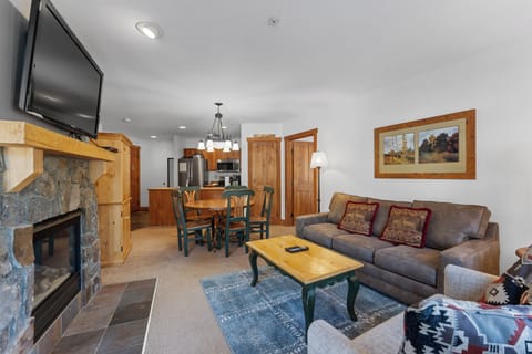 Unwind in your cozy living space with crackling fireplace, plush seating, and open kitchen perfect for mountain retreat memories.