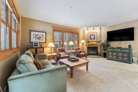 Sink into plush seating by your crackling fireplace, where warm wood tones and mountain views create the perfect retreat.