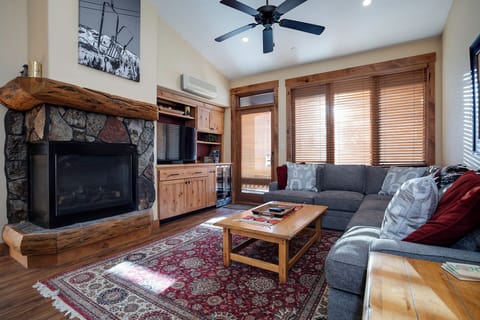Cozy up by the stone fireplace in your rustic living room, where natural wood beams and plush seating create the perfect retreat.