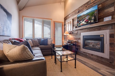 Unwind in your cozy living room where rustic wood meets modern comfort—sink into plush seating by the fireplace while planning adventures.