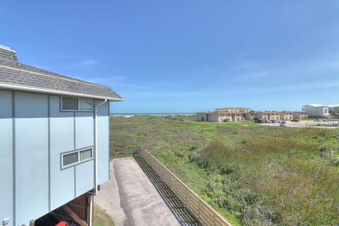 Coastal property with panoramic views of rolling green hills and neighboring buildings under bright blue skies.