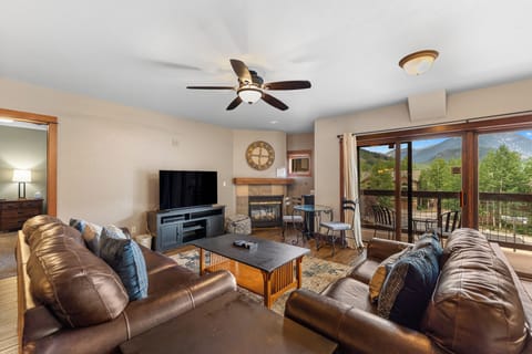 Relax in your spacious living room with mountain views, cozy fireplace, and comfortable leather seating perfect for unwinding after adventure-filled days.