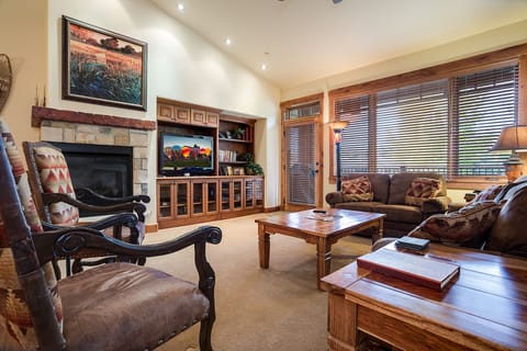Unwind in your cozy living room with rich wood accents, stone fireplace, and plush seating perfect for relaxing evenings.