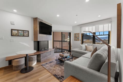 Unwind in your sophisticated living space featuring a cozy fireplace, plush sectional, and mountain views through expansive windows.